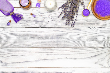 Fototapeta na wymiar Natural bath cosmetic products setting. Dry lavender flowers, sea salt, essential oils, cream and homemade soap on wooden background. Top-down view.