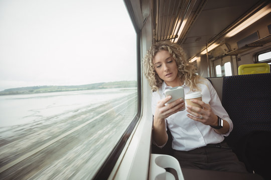 Woman using mobile phone inside train compartment