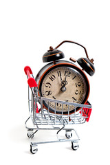 Retro alarm clock in shopping cart on white background.
