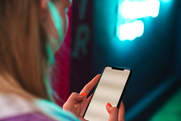 Image of beautiful woman holding smartphone over neon text sign