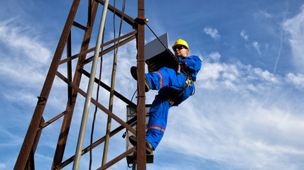 Electrician with yellow helmet and laptop on the electric pole