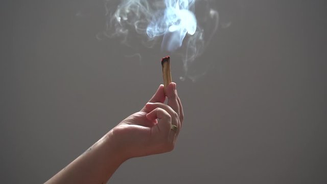 m&atilde;o feminina segurando palo santo queimando