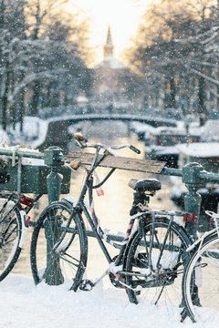 Snow view of a Dutch canal with bicycles in the historic city of Amsterdam