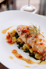 Grill chicken breast with baked potato and kale lemon butter sauce serving in white plate