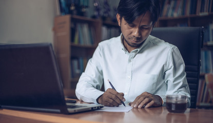Fototapeta premium Young asian business man working with laptop documents sitting at office desk, financial analyst 
