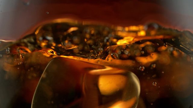 Super Slow Motion Detail Shot of Ice Drop into Glass with Whiskey at 1000fps.