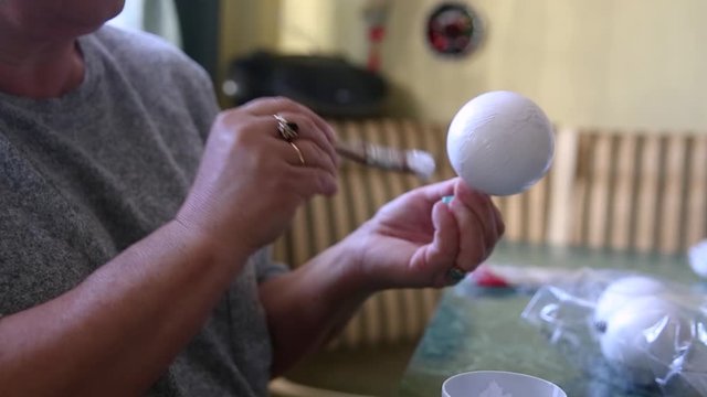 How to make Christmas decorations, close up on hands painting bauble white