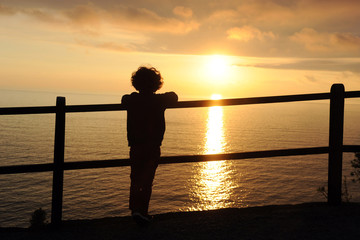 Children boy looking the sea during the sunset