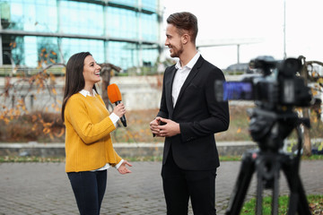 Young journalist interviewing businessman on city street