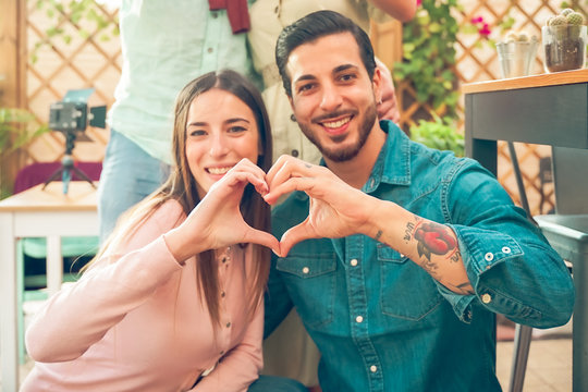 Closeup of couple making heart shape with hands..Beautiful young couple at outside is making heart sign with hands, smiling and looking at camera. Celebrating Saint Valentine's Day. Image