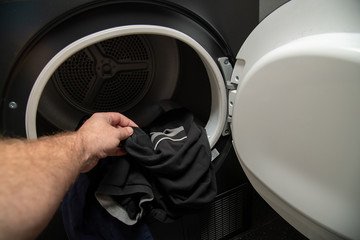 Man pulling clothes out of a condenser tumble dryer