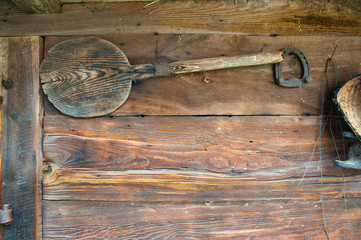 A traditional bread shovel and horseshoe hangs on an old wooden wall