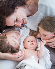 Top view happy positive Young family husband wife and little newborn baby lie on a cozy bed. Concept of a long-awaited child and child care