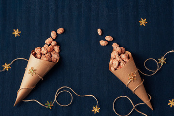 caramel fried almonds in small packets on a blue background with Christmas decor