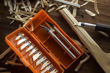 A set of knives for cutting wood lies on a table in a pile of chips.