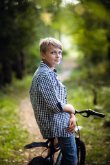 Obraz premium A young boy riding his bike in a summer forest.