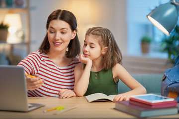 Obraz premium Girl doing homework with mother