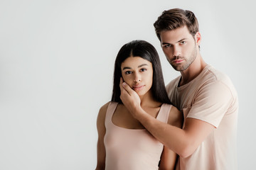 young interracial couple in beige outfit posing together isolated on white