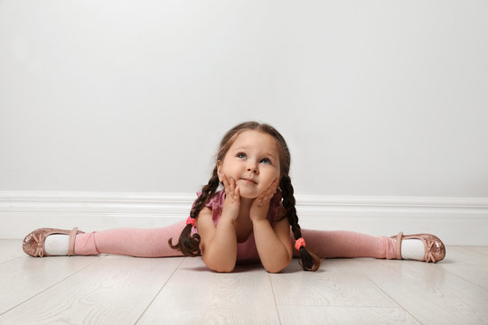Cute little girl on floor near light grey wall