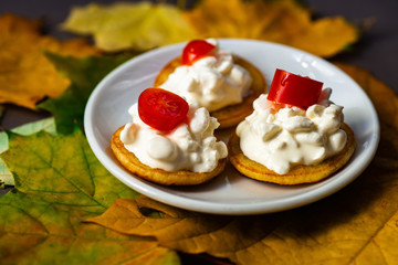 Three pancakes with cottage cheese and tomato on leaves.