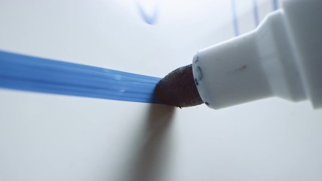 Macro Follow Shot of a Blue Marker Pen Being Held with a Hand. Teacher Writing Equations on a Whiteboard with Mathematical Formulas. Pencil is Connected to the Camera. Gripped Shot.