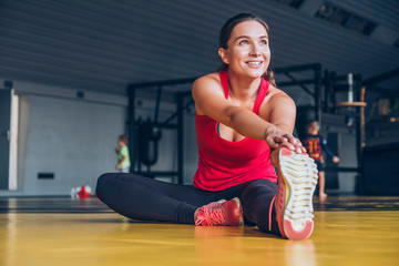 Naklejka premium Slim fit muscular brunette woman exercise in gym, lifting weights and doing pilates. Picture with dark evening mood and film color grading.
