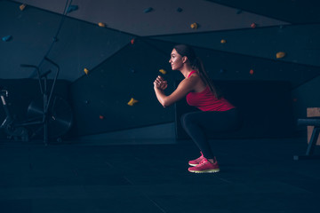 Slim fit muscular brunette woman exercise in gym, lifting weights and doing pilates. Picture with dark evening mood and film color grading.