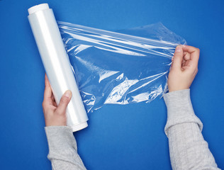 hand hold a large roll of wound white transparent film for wrapping food