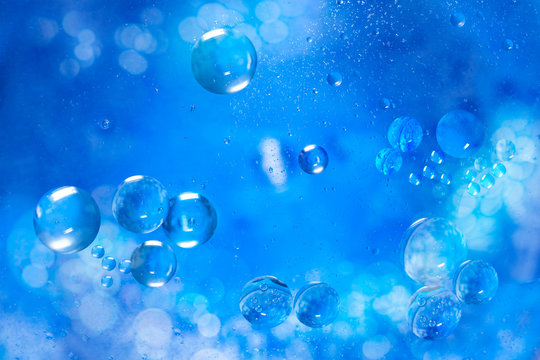 Small air bubbles in sea water. Macro photo. Blue abstract background. Illuminated liquid surface.