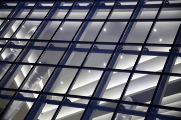 Close-up of structural glazing. Generic modern architecture fragment featuring glass facade wall panels. Abstract urban background. Transparent grid pattern and girders. Geometric polygonal structure.