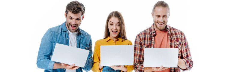 happy young friends holding laptops with open mouths isolated on white, panoramic shot