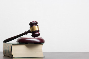 Law concept - Open law book with a wooden judges gavel on table in a courtroom or law enforcement...