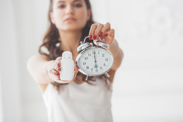 Young woman showing that it`s time to take pills