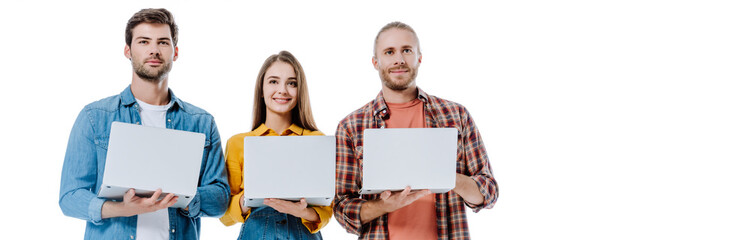 smiling three young friends holding laptops isolated on white, panoramic shot
