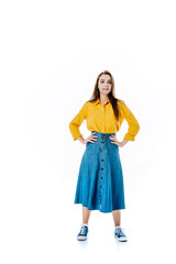 full length view of attractive girl in denim skirt with hands on hips isolated on white