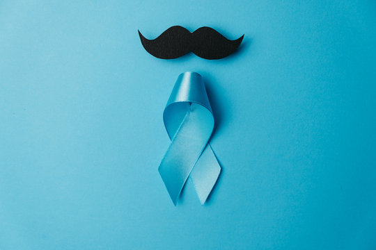 Light blue ribbon with mustache on blue background. Healthcare, International men, Father and World cancer day concept. Flat lay, copy space