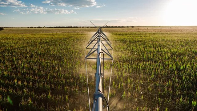 Creative point of view timelapse on top of centre pivot irrigation system at sun set, with cumulous clouds while sprinklers are on to water corn (maize), South Africa.