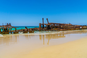 on the beach of fraser island lies the skeleton of a washed-up shipwreck in fine weather