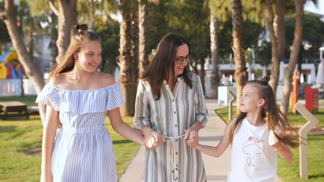 Mom with two lovely daughters 7 and 14 years old strolling down the alley at sunset.