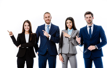 smiling multicultural business people in suits pointing with fingers aside isolated on white