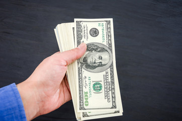 dollars in a hand on a black background. Close-up. Business concept. Much money.