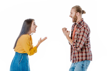 side view of happy young couple in casual outfit showing yeah gesture isolated on white