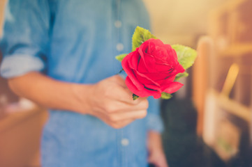 A man reach with a red rose forward.