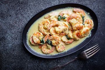 Shrimps in cream sauce with Coconut milk on a plate over black background, top view or view from above, flat lay