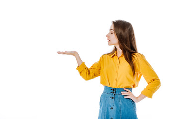 attractive girl pointing with hand aside with hand on hip isolated on white