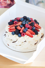 Meringue pavlova cake decorated with fresh berries, strawberries, raspberries, blueberries and red currant. 
