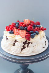 Meringue pavlova cake decorated with fresh berries, strawberries, raspberries, blueberries and red currant. 