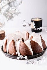 Homemade Orange Poppy seed Almond Bundt Cake, silver artificial christmas tree and perfumed candle on grey concrete table. Christmas cake. Selective focus