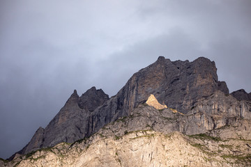 Scenic high rocky mountain peak in sunset light.  Shadow and light. Sloping inaccessible surface of Rocky mountain. Dramatic overcast sky. Alpine landscape romantic, Switzerland.