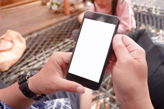 Mockup picture of business woman’s hands holding smart phone with white blank screen in modern place.